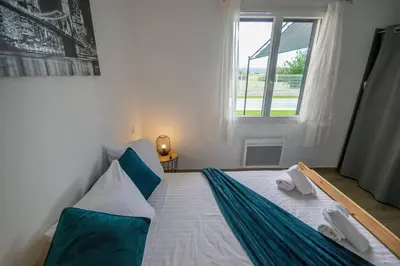 a white bed with blue pillows and a window at La casa du lac vue imprenable in Homps