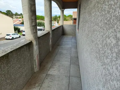 a corridor of a building with columns and a street at Appartement Familial proche de Carcassonne in Villemoustaussou