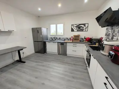 a large kitchen with white cabinets and stainless steel appliances at Appartement Familial proche de Carcassonne in Villemoustaussou