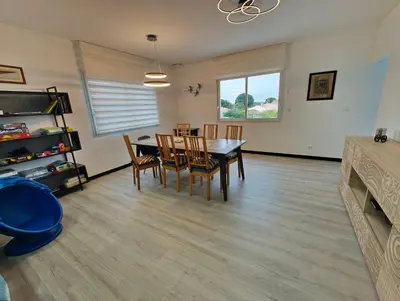a dining room and living room with a table and chairs at Appartement Familial proche de Carcassonne in Villemoustaussou