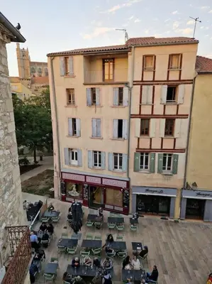 a group of people sitting at tables in front of a building at Appartement cosy hypercentre in Narbonne