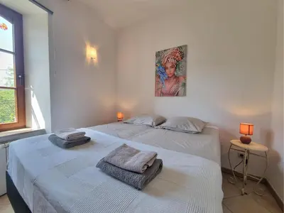 two beds in a white bedroom with a painting on the wall at La Roche 6 in Aigues-Vives