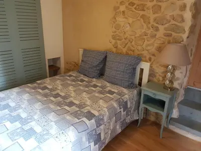 a bedroom with a bed and a stone wall at La Félicita - Gîte de charme proche de Narbonne in Moussan
