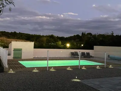 a swimming pool behind a fence at night at Lily in Escales