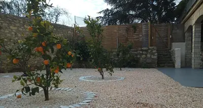 two orange trees in a garden with a fence at Love Room Emoi de toi in Sigean