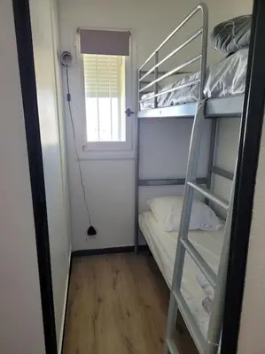 a small room with a bunk bed and a window at Appartement en résidence avec vue et accès au port in Gruissan