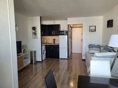 a living room with a television on a cabinet at Appartement en résidence avec vue et accès au port in Gruissan