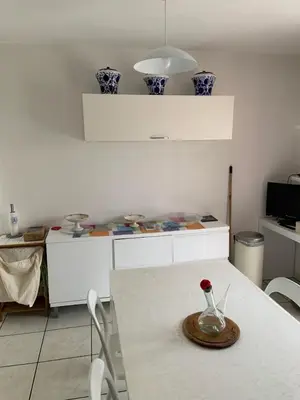 a white kitchen with a table with a vase on it at les amandiers in Salses-le-Chateau