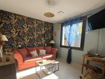 an orange couch in a living room with a wallpaper at Les Amandiers in Sallèles-dʼAude