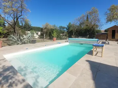 a swimming pool with a chair in a yard at Les Amandiers in Sallèles-dʼAude