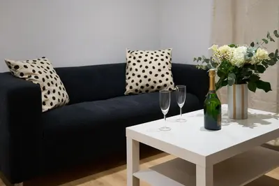a black couch with a table with wine glasses and flowers at La Villa Orange - Proche cité médiévale et centre ville à pied in Carcassonne
