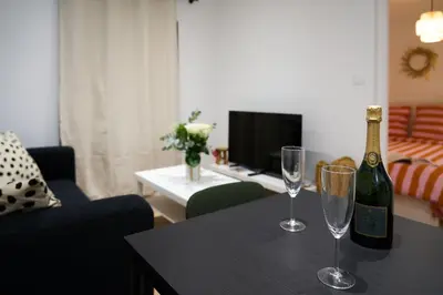 a bottle of champagne and two wine glasses on a table at La Villa Orange - Proche cité médiévale et centre ville à pied in Carcassonne