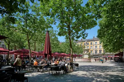 a group of people sitting at tables with umbrellas at La Villa Orange - Proche cité médiévale et centre ville à pied in Carcassonne