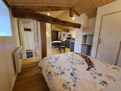 a bedroom with a large bed and a kitchen at Refuge Insolite avec balnéo privative en forêt in Pont-de-Larn