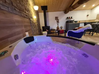 a bath tub filled with pink water in a room at Refuge Insolite avec balnéo privative en forêt in Pont-de-Larn