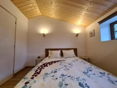 a bedroom with a large bed with a wooden ceiling at Refuge Insolite avec balnéo privative en forêt in Pont-de-Larn