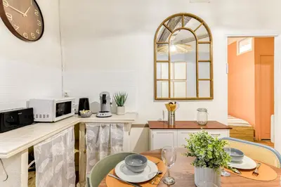 a kitchen with a table and a clock on the wall at El Quatro - Wifi - Central - tout équipé in Carcassonne