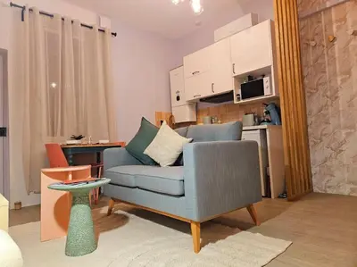 a living room with a blue chair and a kitchen at Le Pastel YourHostHelper in Narbonne