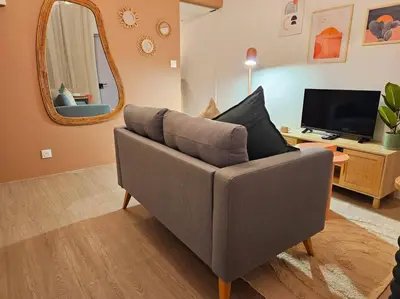 a living room with a grey couch and a mirror at Le Pastel YourHostHelper in Narbonne