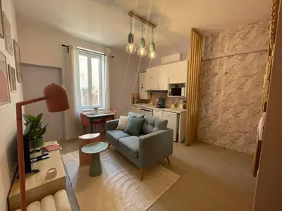 a living room with a couch and a kitchen at Le Pastel YourHostHelper in Narbonne