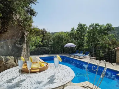 a table with drinks and chairs next to a swimming pool at La Roche 10 in Aigues-Vives