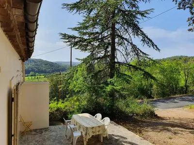 a table and chairs on a porch with a tree at La Roche 10 in Aigues-Vives