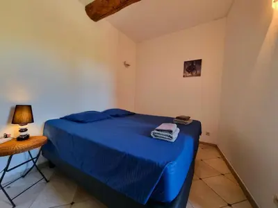 a bedroom with a blue bed and a table at La Roche 10 in Aigues-Vives