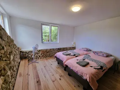 a bedroom with two beds and a stone wall at La Roche 10 in Aigues-Vives