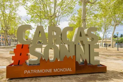 a sign for a park with trees in the background at La magie de Carnot Meublé de tourisme 3 étoiles in Carcassonne
