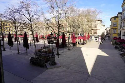 a street with tables and umbrellas in a city at La magie de Carnot Meublé de tourisme 3 étoiles in Carcassonne