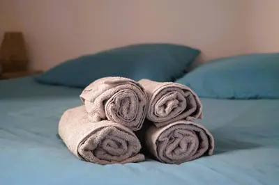 a pile of towels sitting on top of a bed at La magie de Carnot Meublé de tourisme 3 étoiles in Carcassonne