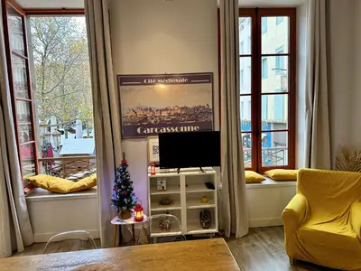 a living room with a television and windows with a christmas tree at La magie de Carnot Meublé de tourisme 3 étoiles in Carcassonne