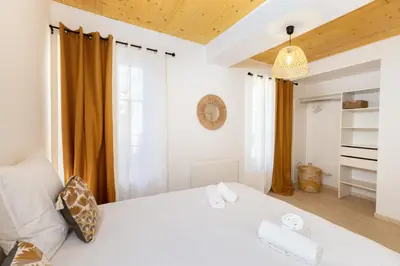 a bedroom with a white bed with orange curtains at L'Impasse d'Adam Free Parking in Carcassonne