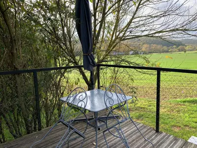 a table with an umbrella on top of a porch at Roulotte et Nature in Mirepoix