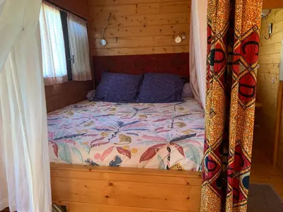 a bed in a wooden cabin with a canopy at Roulotte et Nature in Mirepoix