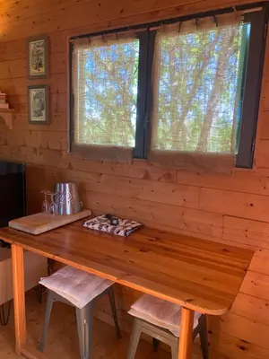 a wooden table in a cabin with two windows at Roulotte et Nature in Mirepoix