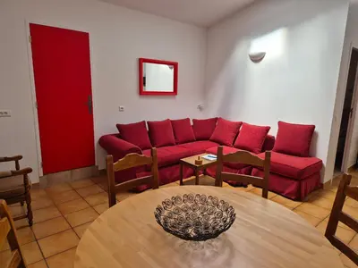 a living room with a red couch and a table at Au Pont Romain Gites in Caunes-Minervois