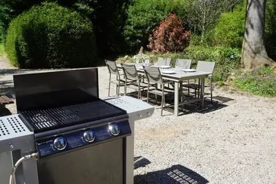 a grill and a table with chairs and a table with at Au Pont Romain Gites in Caunes-Minervois