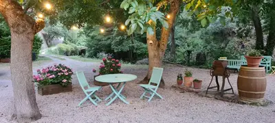 a table and chairs under a tree with lights at Au Pont Romain Gites in Caunes-Minervois