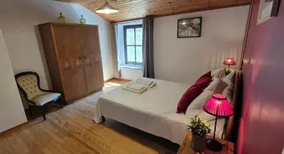 a bedroom with a bed with a lamp and a chair at Au Pont Romain Gites in Caunes-Minervois