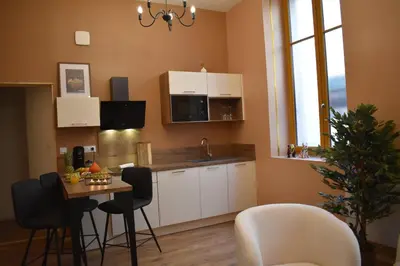 a kitchen with white cabinets and a table with chairs at La République d'Emmanuel in Carcassonne