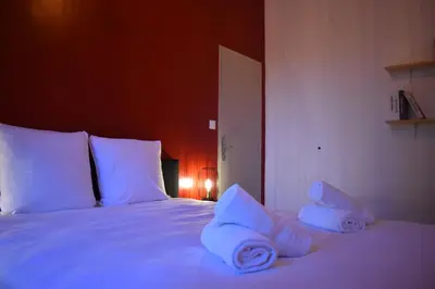 a bedroom with a white bed with towels on it at La République d'Emmanuel in Carcassonne