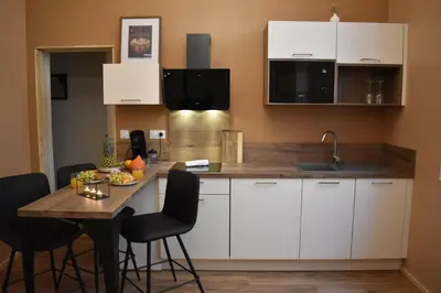 a kitchen with white cabinets and a wooden table at La République d'Emmanuel in Carcassonne