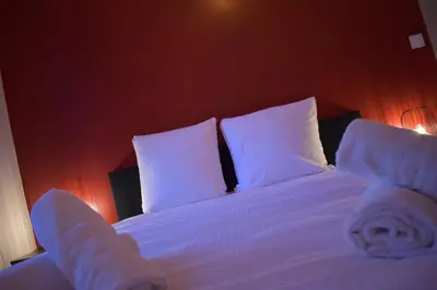 a bedroom with a bed with white sheets and pillows at La République d'Emmanuel in Carcassonne