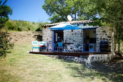 a stone house with a table and chairs and an umbrella at Moulin de Perle in Fosse