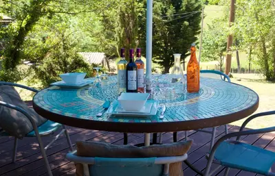 a table with wine bottles and glasses on a patio at Moulin de Perle in Fosse