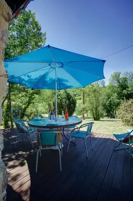 a table and chairs with a blue umbrella on a deck at Moulin de Perle in Fosse