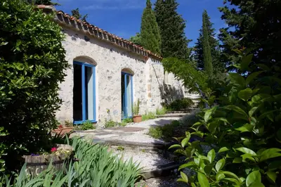 an old stone house with blue windows and plants at Moulin de Perle in Fosse