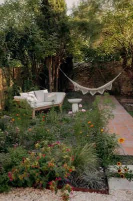 a hammock in a garden with a bench and flowers at Pausette in Fanjeaux