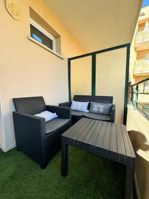 two wicker chairs and a table on a balcony at Narb'home, Cosy , Parking, Balcon in Narbonne